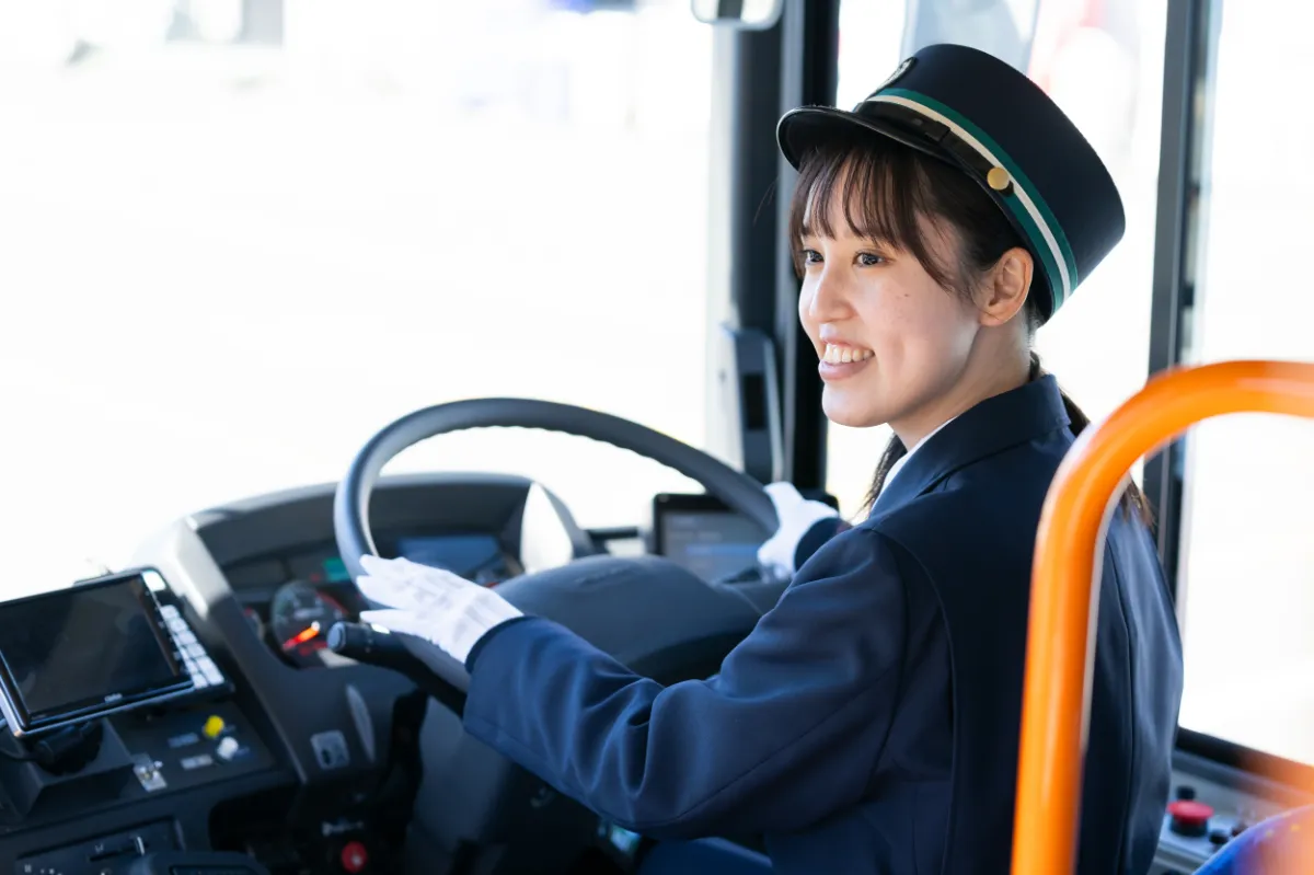女性社員が運転席から後ろを振り返って笑っている写真